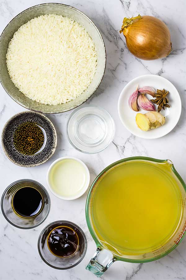 Ingredients for steamed Chinese rice in individual bowls on a marble countertop