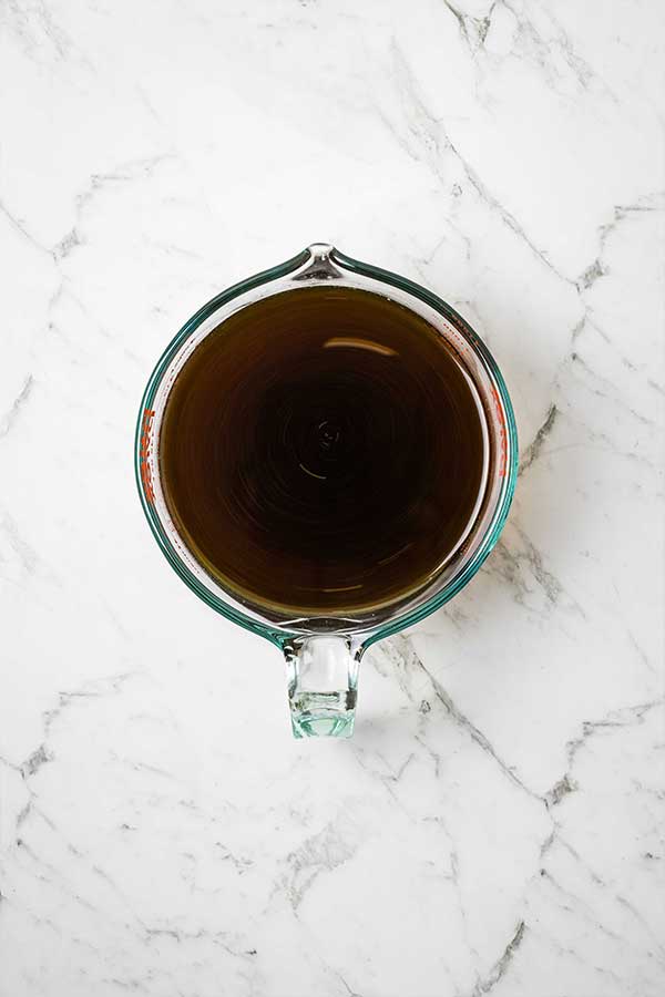 A glass jug with a dark liquid on a marble countertop