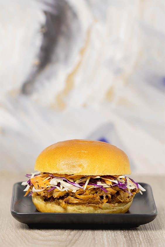 A golden brown bread roll with pulled meat and coleslaw