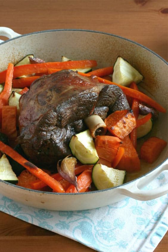 A casserole dish filled with steam oven roast lamb and vegetables.