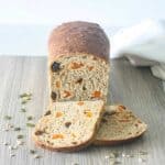 a loaf of bread with apricots, dates and seeds, with two slices cut off the end