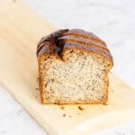 The sliced end of a loaf of banana bread on a wooden board on a marble counter