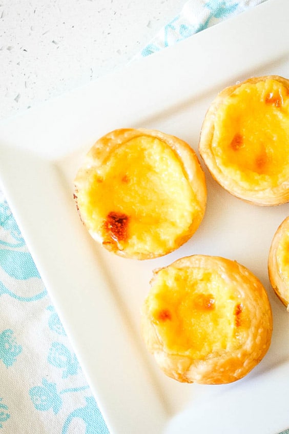 a plate pf Portugese Custard Tarts on a blue and white patterned napkin