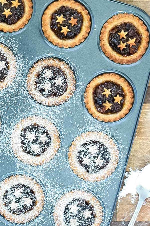 a muffin tray with pies decorated with pastry stars, some sprinkled with icing sugar