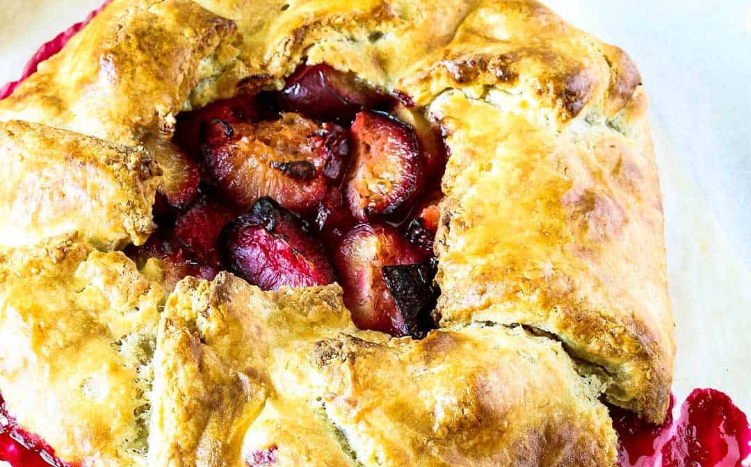 a close up of a golden and flaky tart with roasted plums