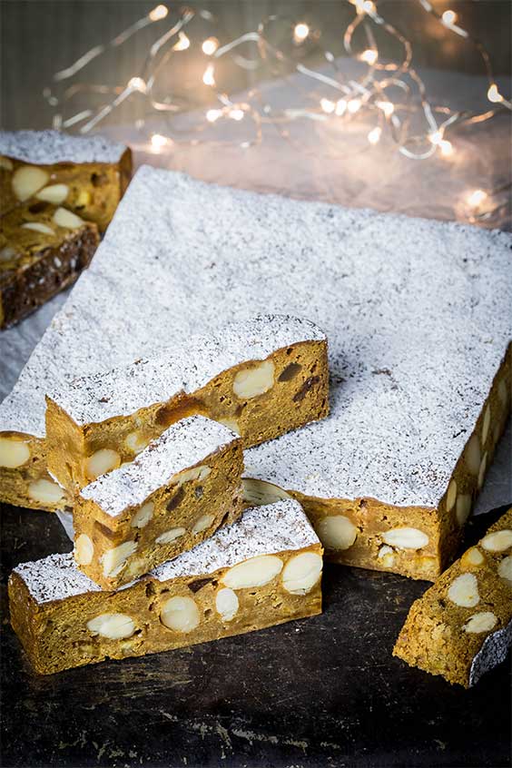 twinkly lights surrounding a cut up white chocolate panforte cake