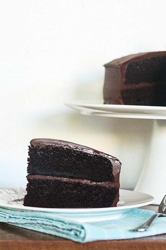 a slice of steam oven chocolate cake, served on a white plate with fork alongside