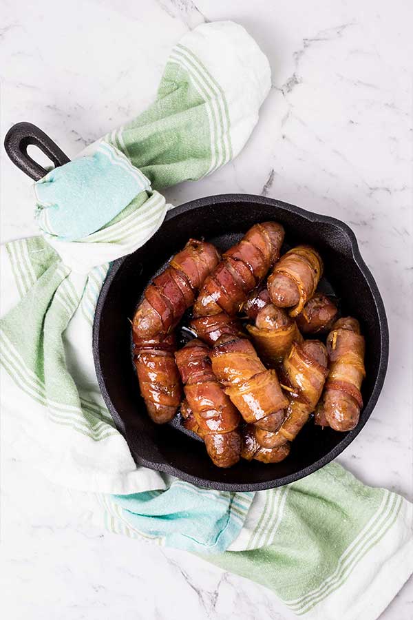 a skillet of bacon wrapped sausages