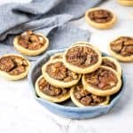 mini pecan pies in a blue pottery dish with more in the background