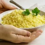 bowl of couscous being presented by two hands