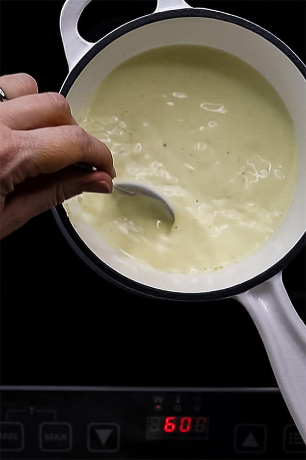 milk, cream and vanilla bean in a white saucepan