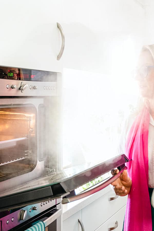 woman with pink scarf opens oven