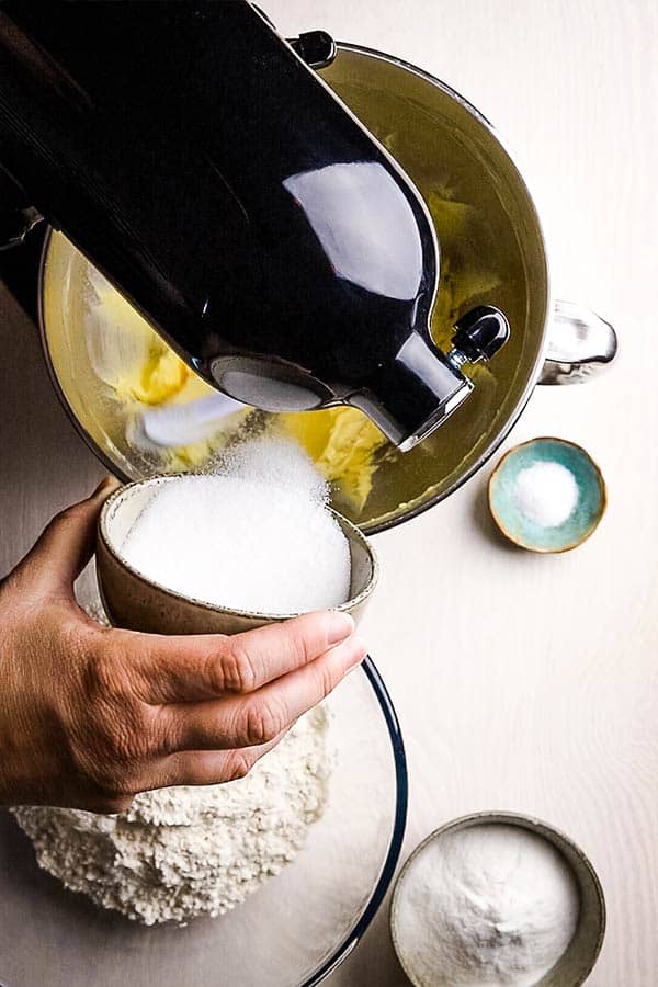 sugar being poured into butter in a mixer