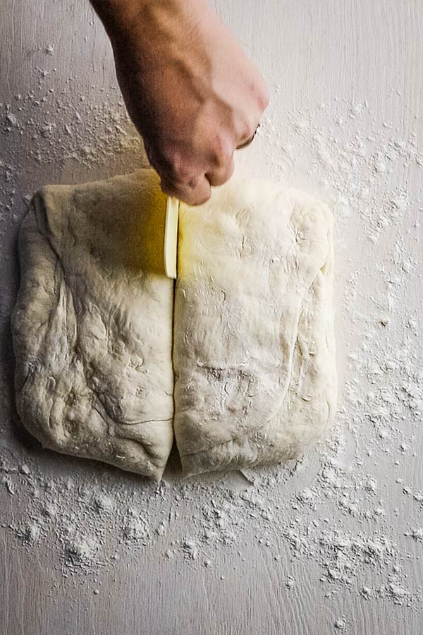 a square of dough being cut in half with a dough cutter