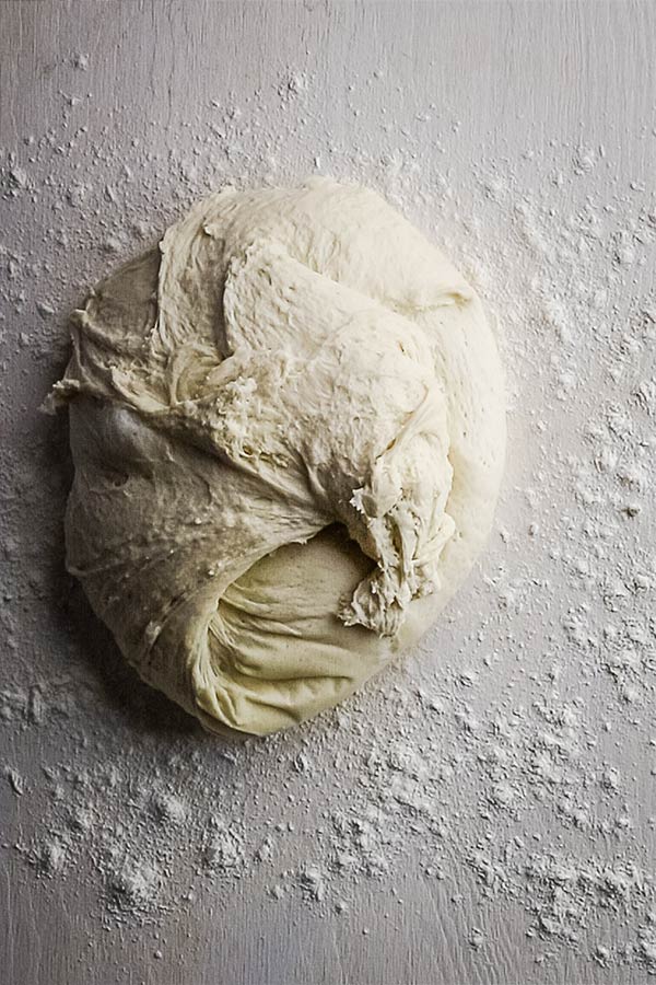 A large ball of dough on a flour dusted board
