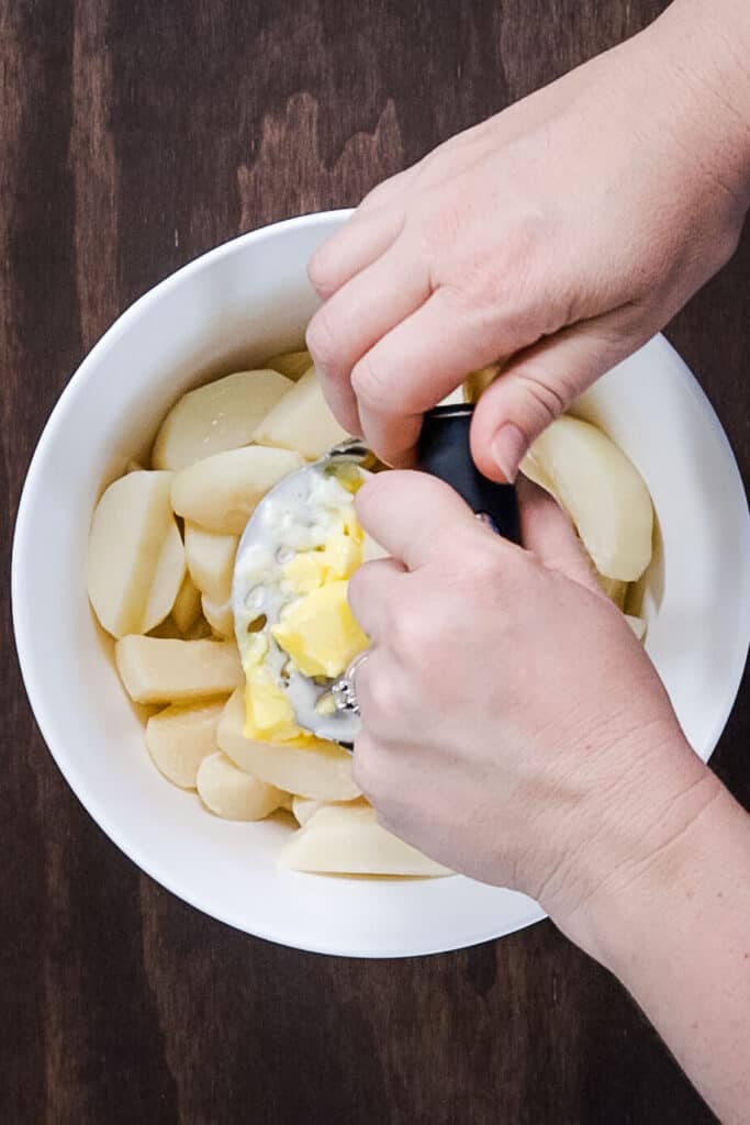 potatoes being mashed in bowl