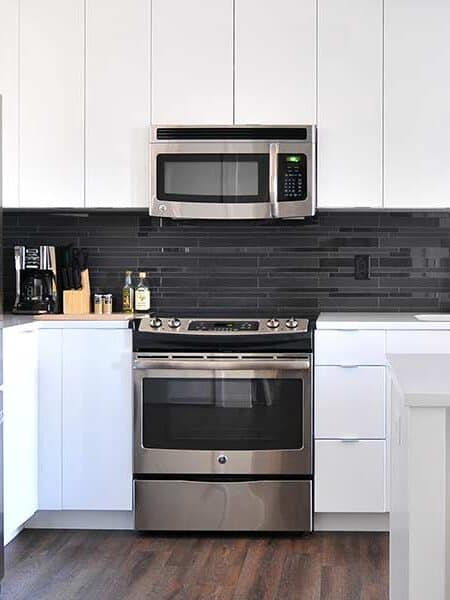 A kitchen with white benches and a large steam oven and range with a microwave above it