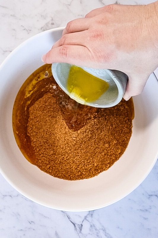 Pouring melted butter onto the crumbs in a big bowl