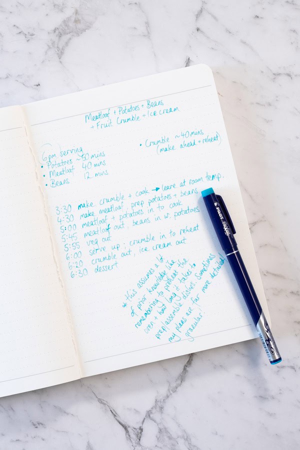 A notebook page filled with handwritten notes, outlining a timed meal plan for meatloaf, potatoes and beans.