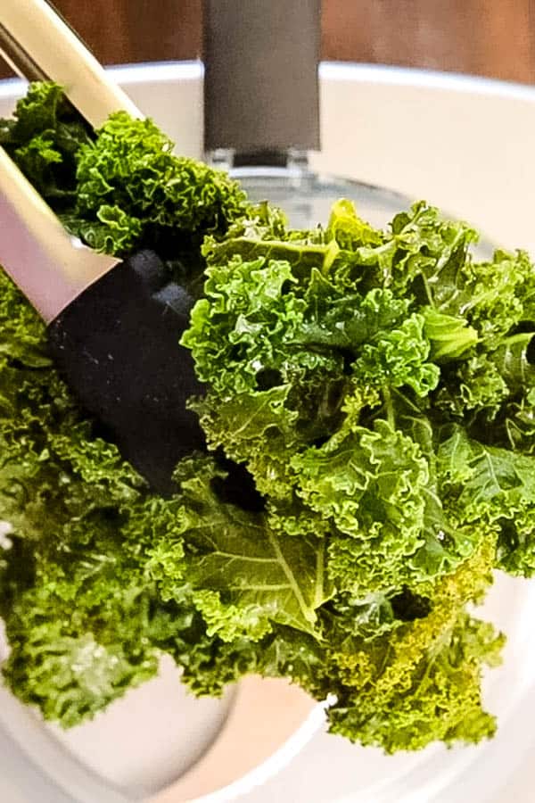 putting steamed kale leaves into a food processor