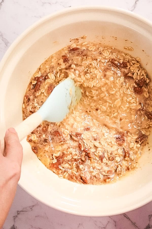 Stirring a bowl of oats, nuts and liquid for baked oatmeal. 
