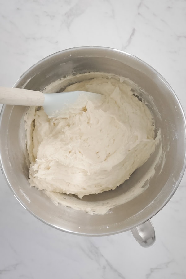 Scraping cake batter with a spatula in a mixing bowl.