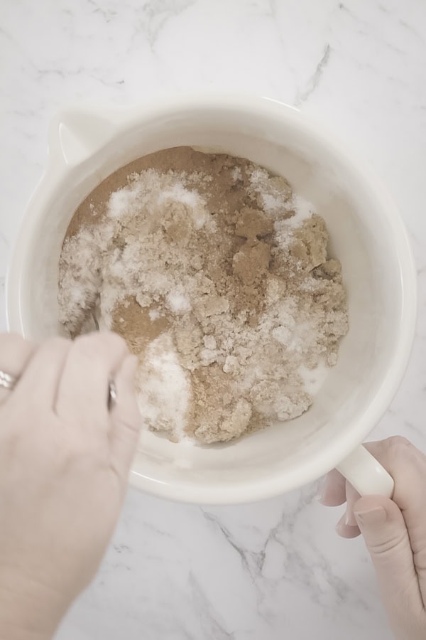 Mixing sugars and spices in a bowl for apple crumb cake topping.