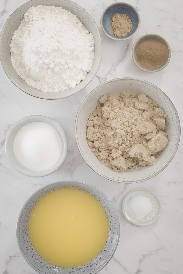  Various crumb topping ingredients in separate bowls on a marble surface.