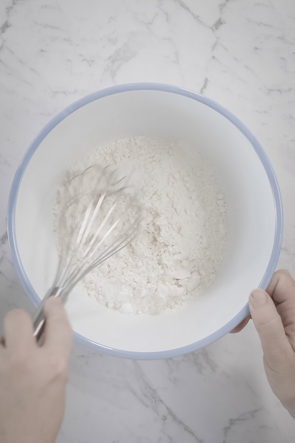 Whisking the dry ingredients in a white and blue mixing bowl.