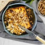 Golden baked feta topped with chopped walnuts and honey in a blue dish, served with crusty bread.