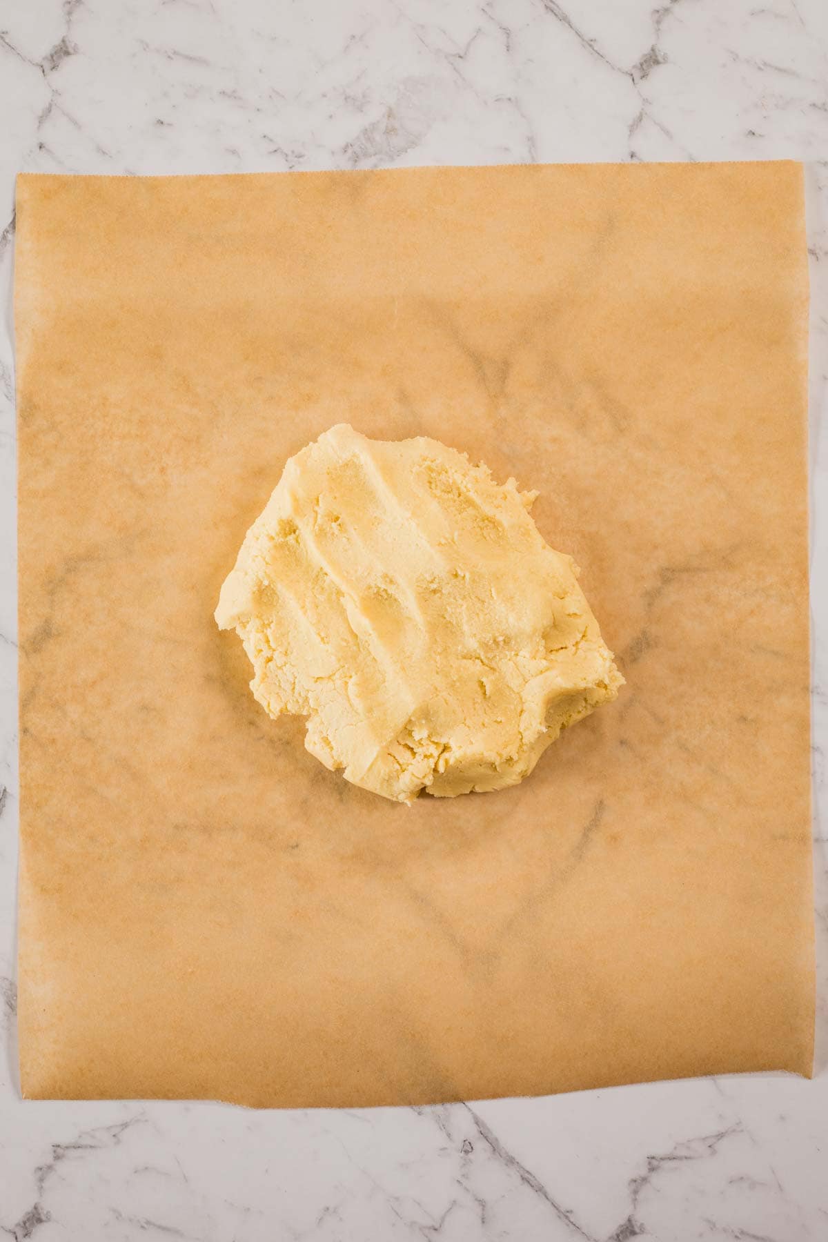 A blob of butter cookie dough on top of parchment paper.