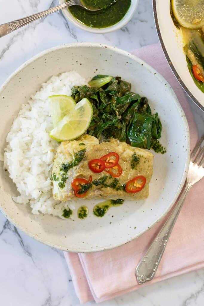 Quick and easy coconut steamed fish with green curry, fresh greens and lime slices. 