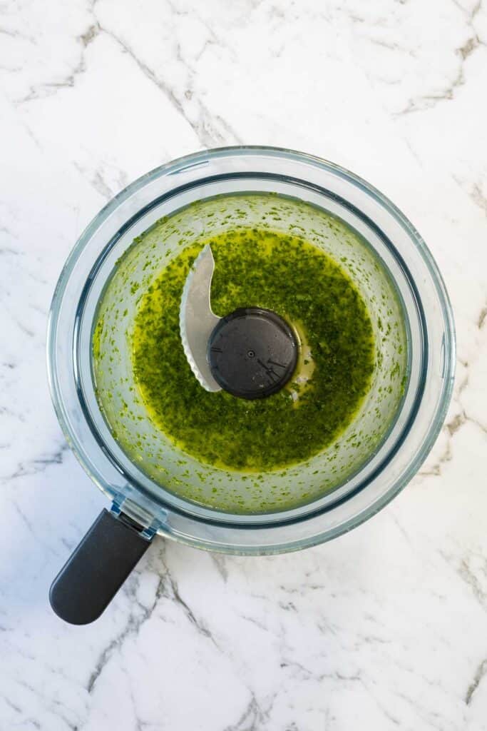 A top down view of coriander oil in a food processor, with the lid off. 