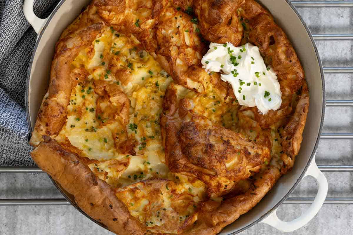 Landscape view of savory Dutch Baby Pancake with cheese, chives, and sour cream.