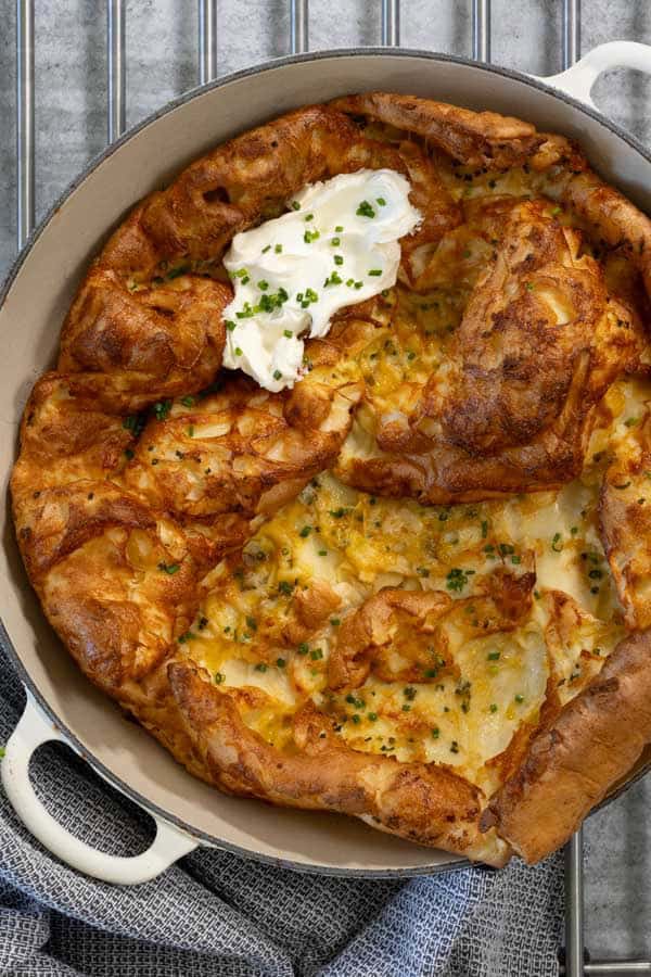 Savory Dutch Baby Pancake with melted cheese, chives, and a dollop of sour cream.