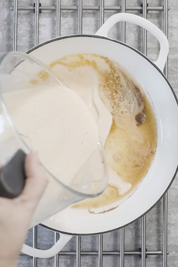 Pouring Dutch Baby Pancake batter into a hot pan with melted butter.