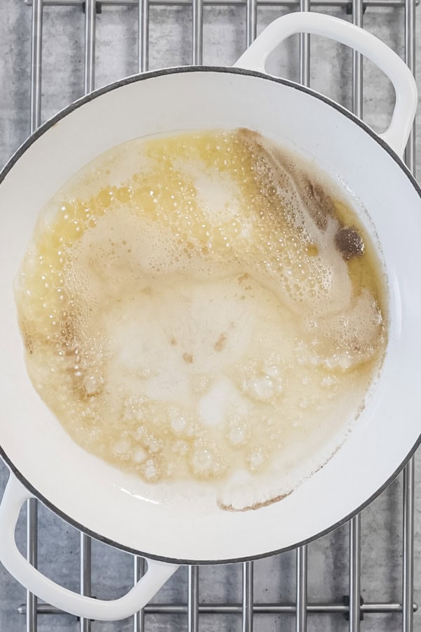 Melted butter bubbling in a white pan for Dutch Baby Pancake.