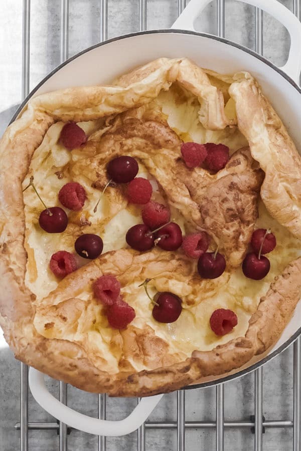 Baked Dutch Baby Pancake topped with raspberries and cherries.