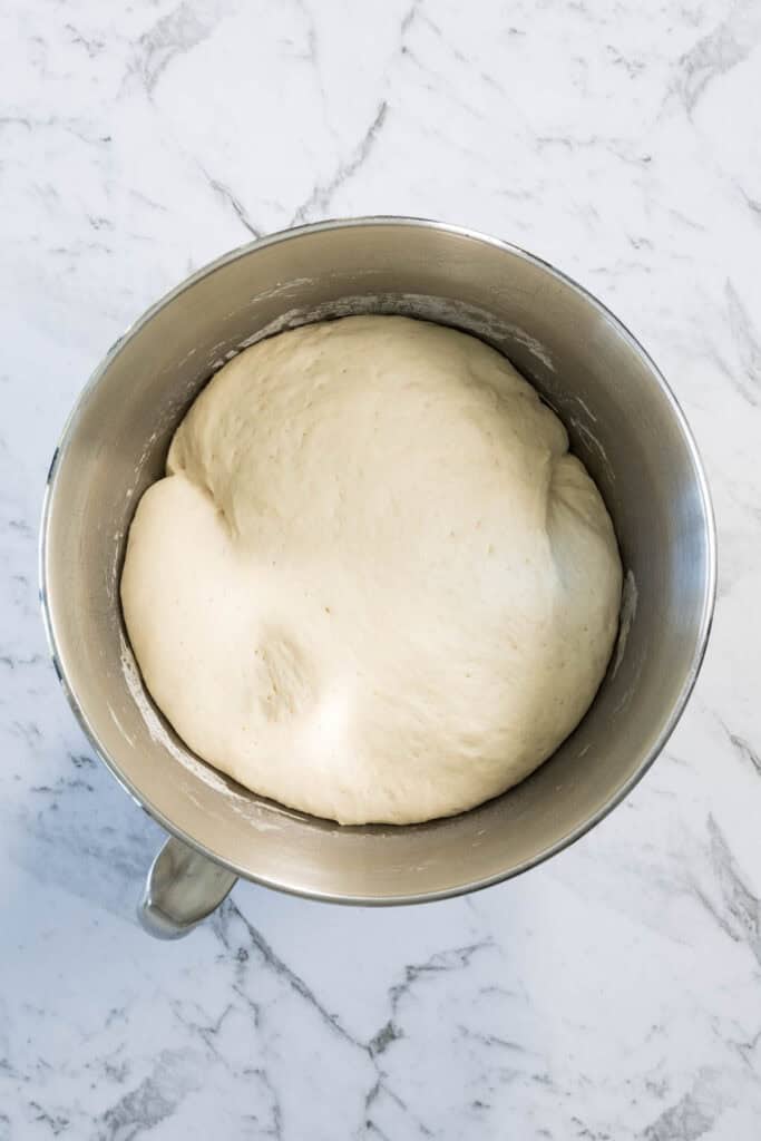 Proofed dough has doubled in size, filling the stainless steel mixing bowl for zaatar bagels.