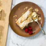 A slice of lemon cheesecake Danish on a plate with fresh raspberries.
