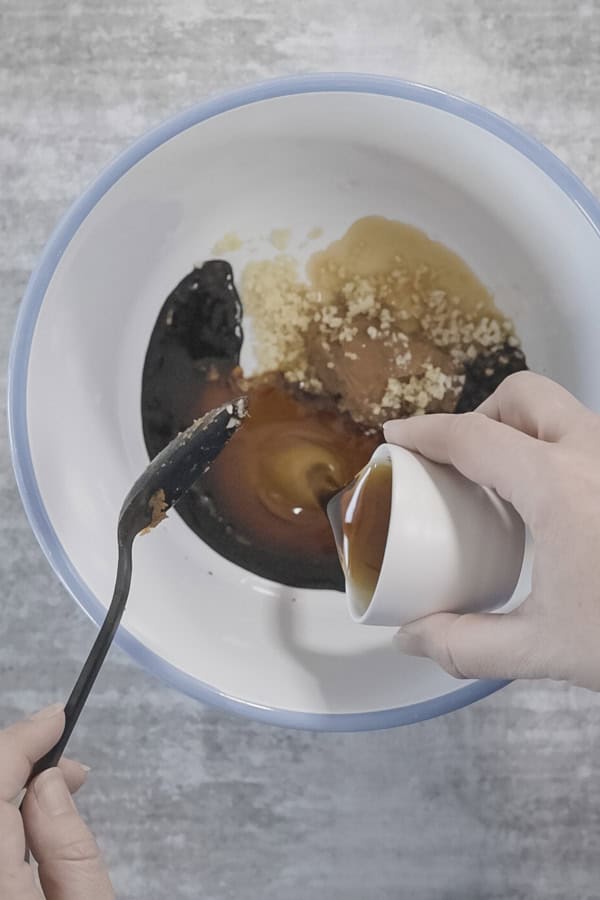 A white bowl with ingredients being mixed together for miso maple chicken.