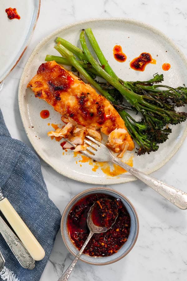 Roasted salmon and broccolini on a plate, drizzled with chili oil.