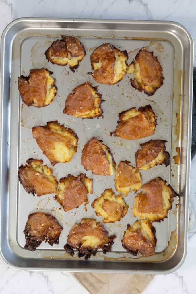 Crispy roasted smashed potatoes on a metal sheet pan. 