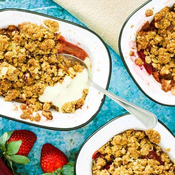 individual enamel dishes filled with red fruit and crumble topping