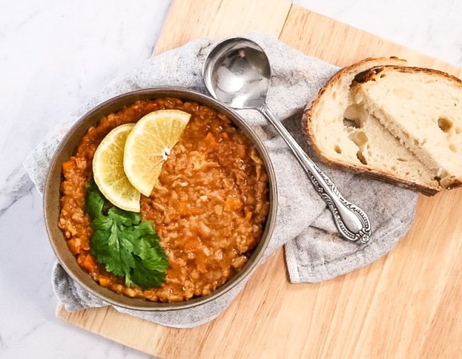 landscape view of arabic lentil soup in a bowl with spoon and slices of bread