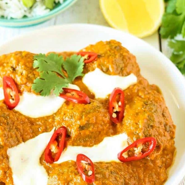 A zoomed in picture of a bowl of beef kofta curry garnished with yoghurt and sliced chilli