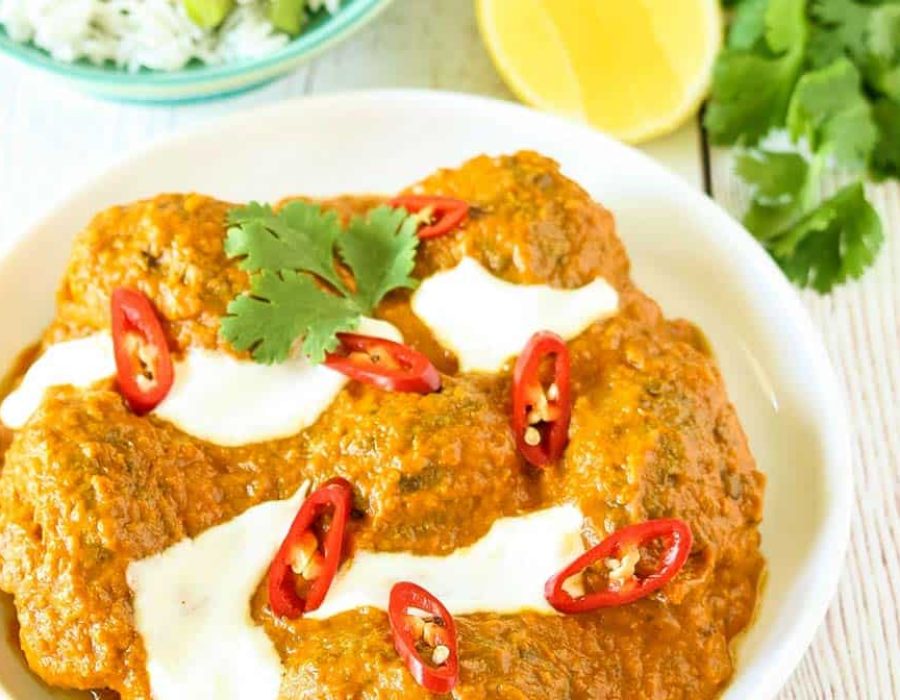 A zoomed in picture of a bowl of beef kofta curry garnished with yoghurt and sliced chilli