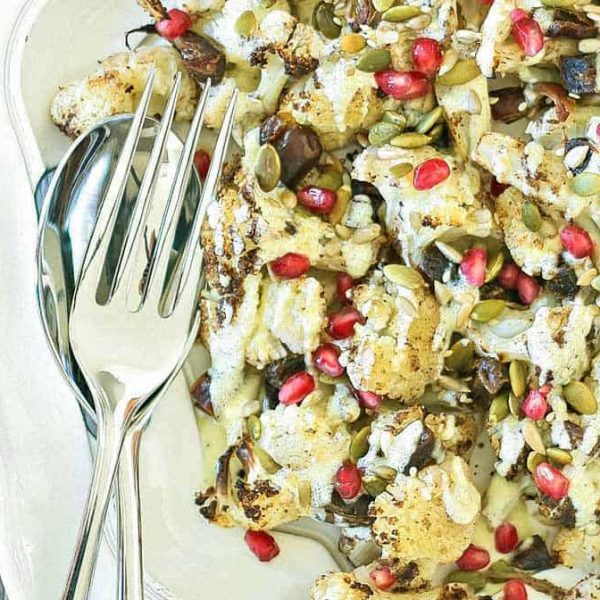 Cauliflower salad on a white scalloped edge plate with cutlery beside it