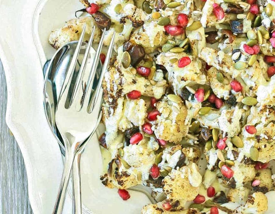 Cauliflower salad on a white scalloped edge plate with cutlery beside it