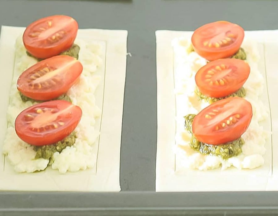2 raw puff pastry cherry tomato tarts on a baking tray